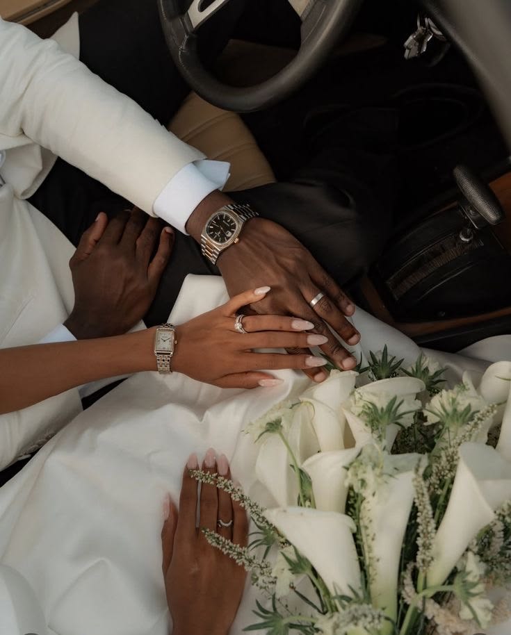 Newlyweds holding hands beside a white bridal bouquet