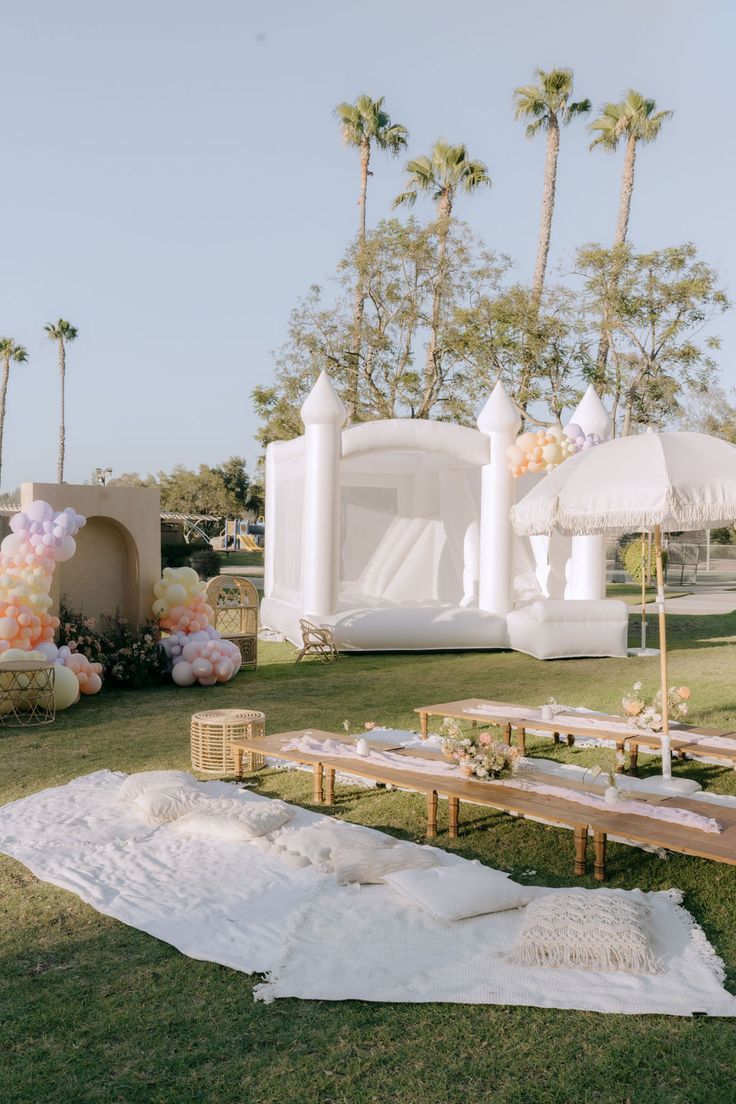 Outdoor kids' lounge with low tables, floor cushions and a white bounce castle.